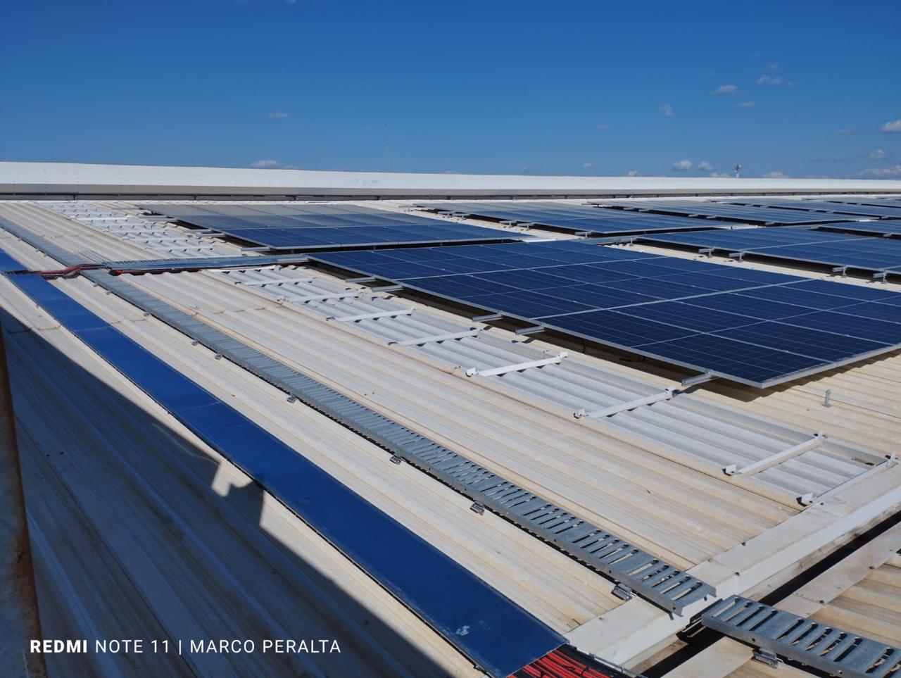 Paneles solares instalados sobre un techo de lámina bajo un cielo azul
